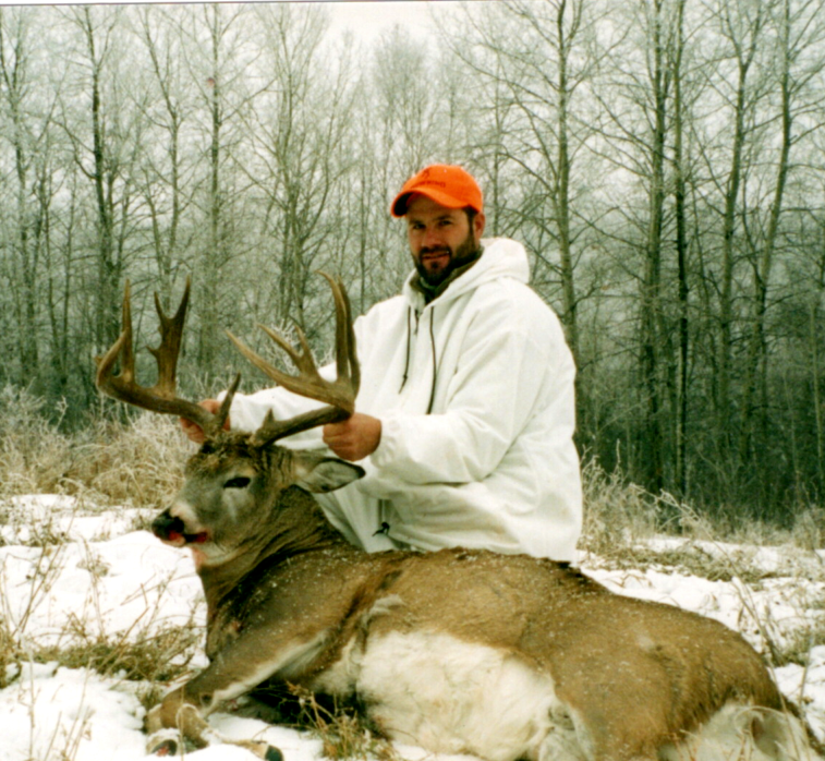 Chuck Main with a mature buck on snow-covered hunting land