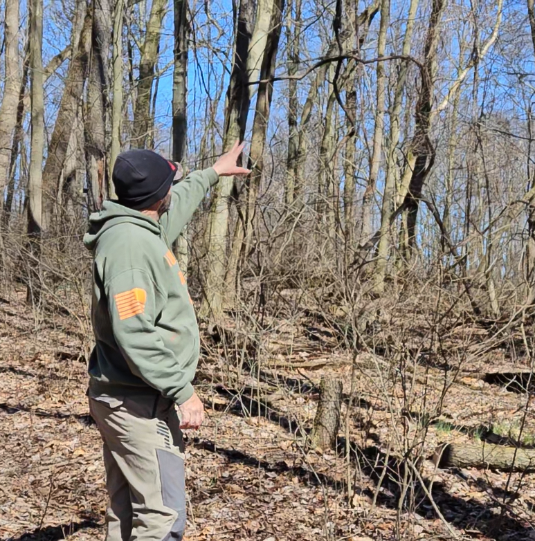 Chuck Main pointing to a section of managed land while discussing whitetail habitat development