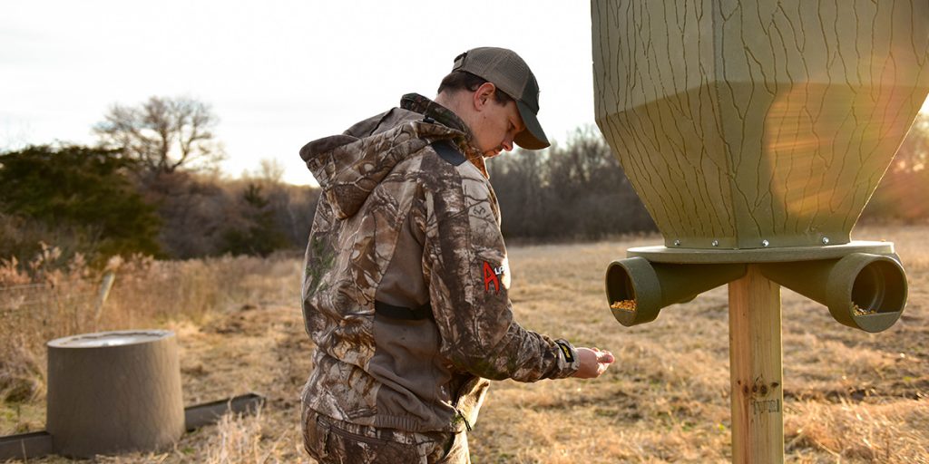 Gravity deer feeder positioned in a wooded area, ensuring a steady, natural feed supply for whitetail deer and other wildlife.